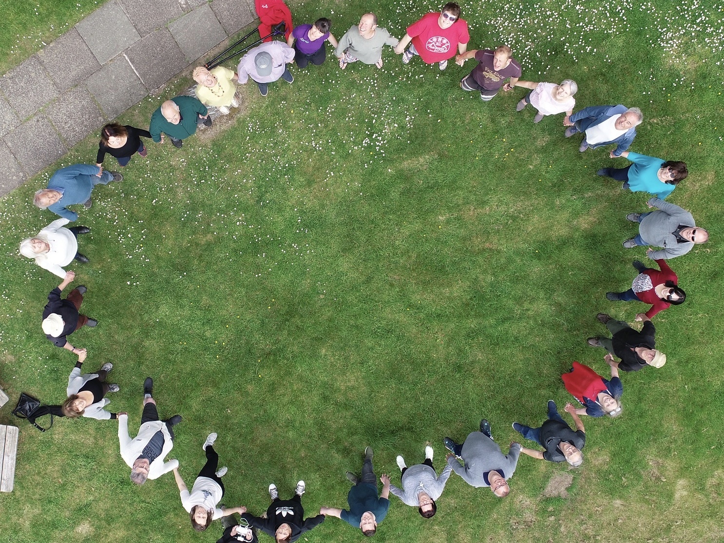 An ariel picture from a drone of adults in a circle joining hands and looking up